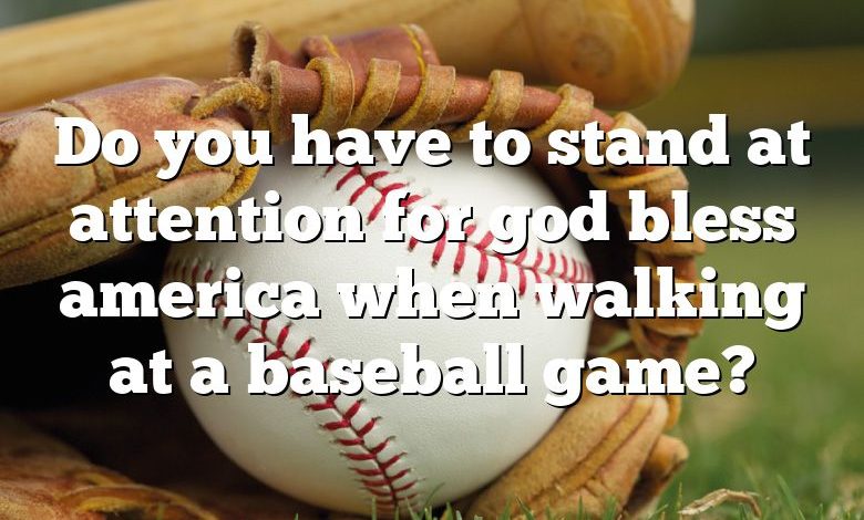 Do you have to stand at attention for god bless america when walking at a baseball game?