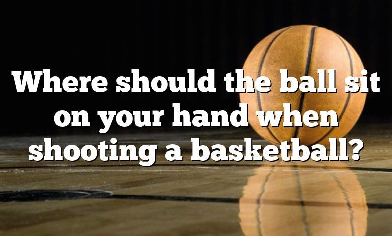 Where should the ball sit on your hand when shooting a basketball?